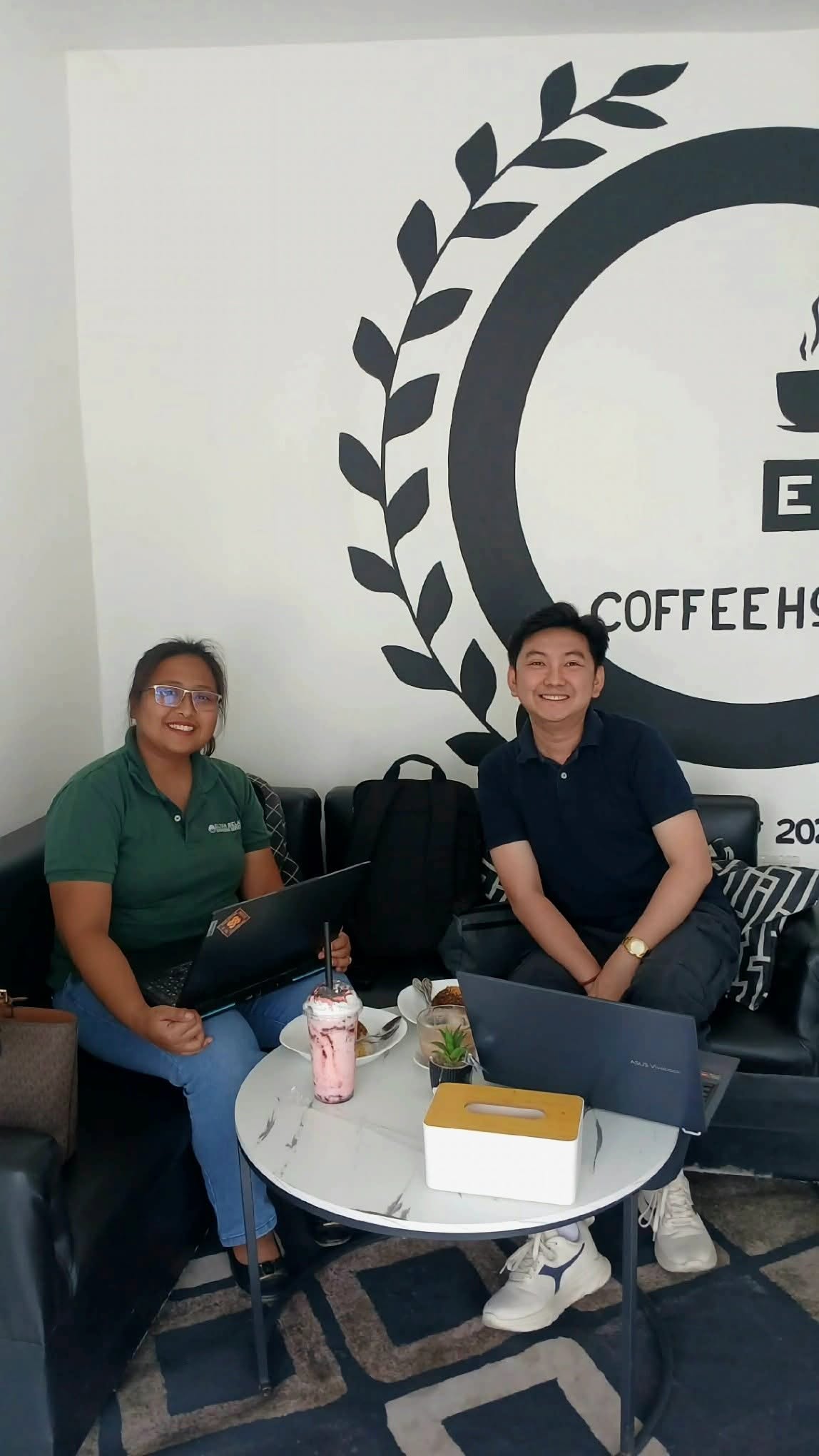 Jayson and a business owner with laptops during a consulting session at a coffeehouse