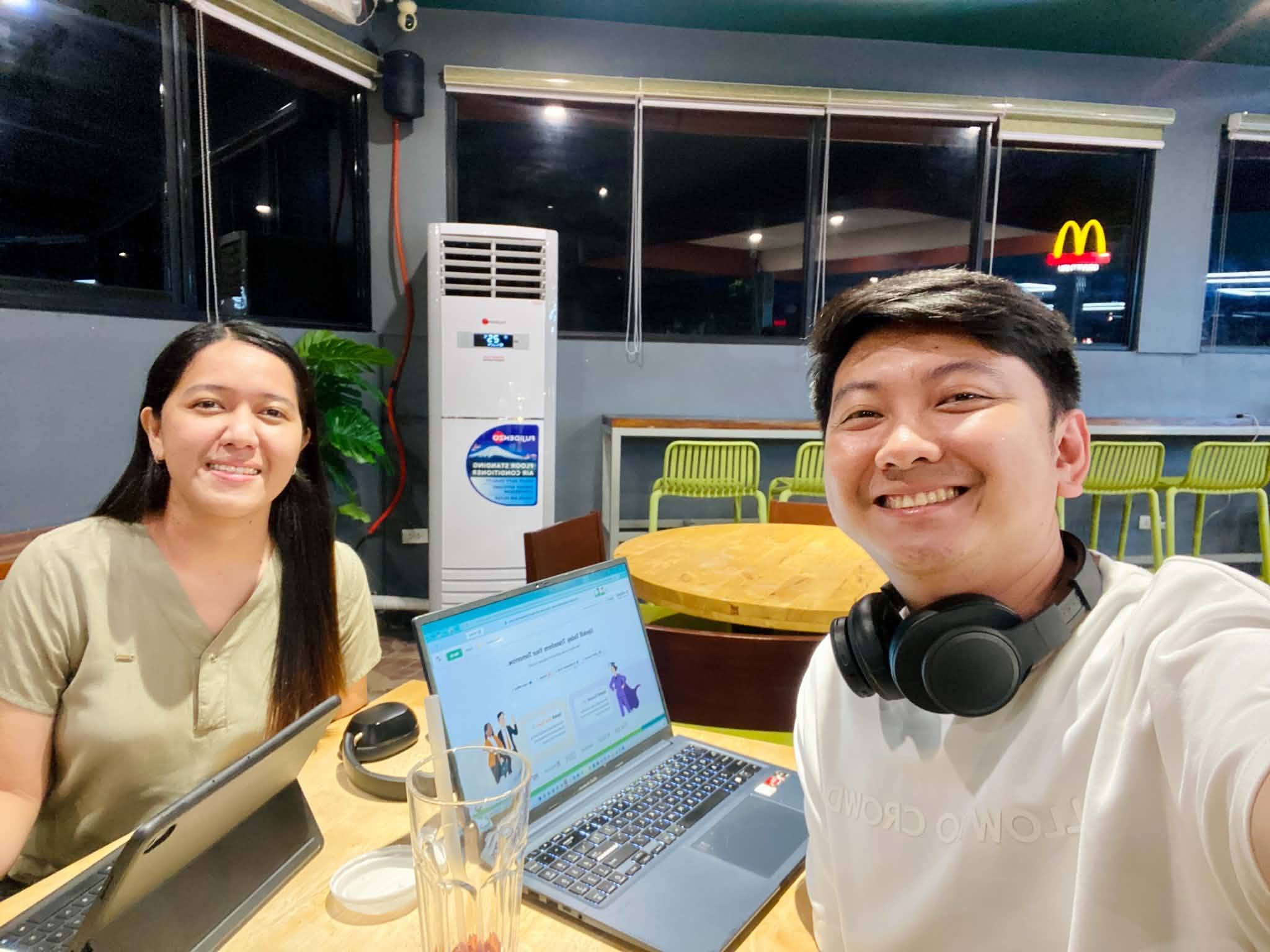 Jayson reviewing work on a laptop with a mentee during an evening consulting session