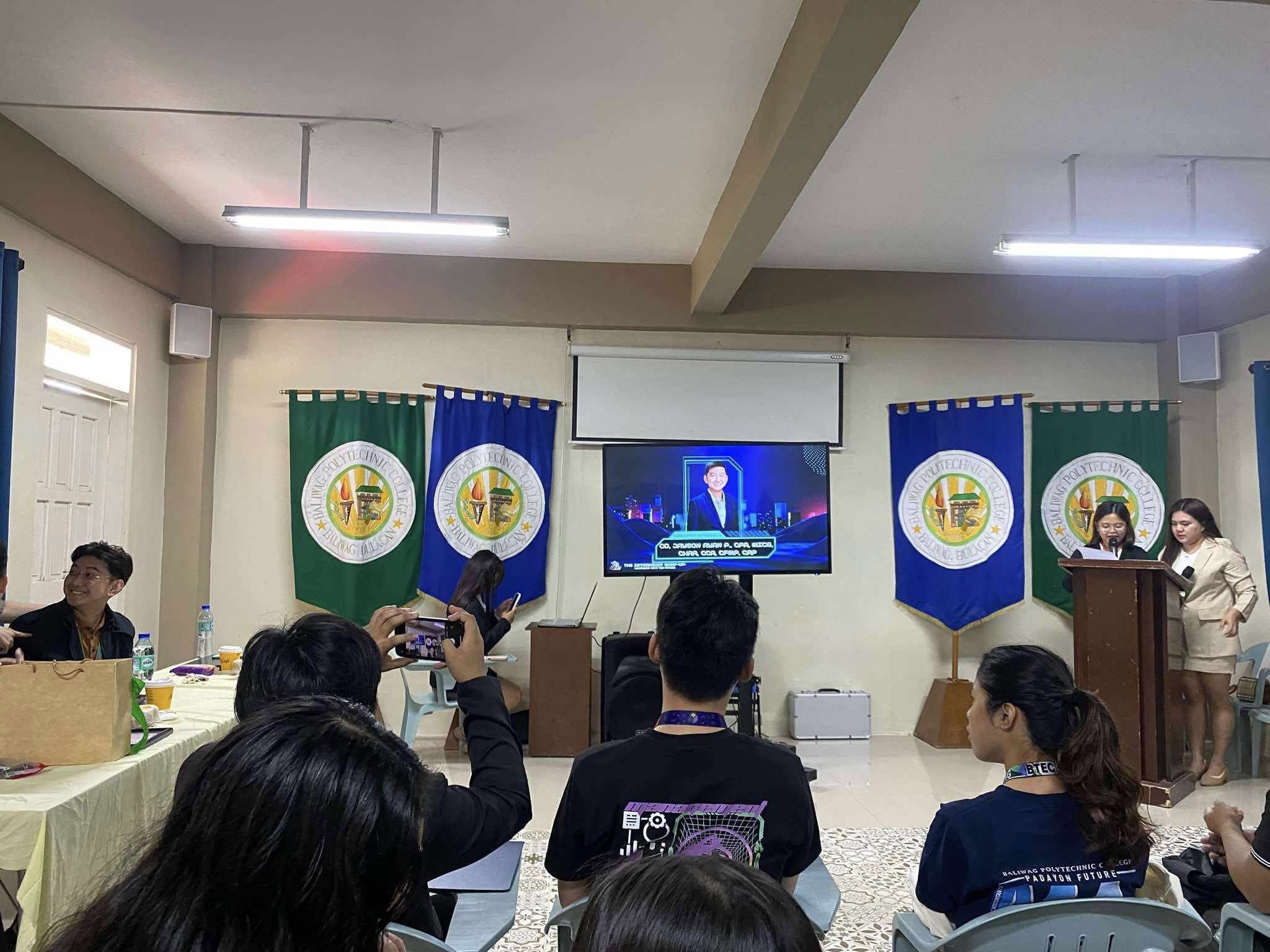 Audience watching Jayson’s introduction video between Baliwag Polytechnic College banners