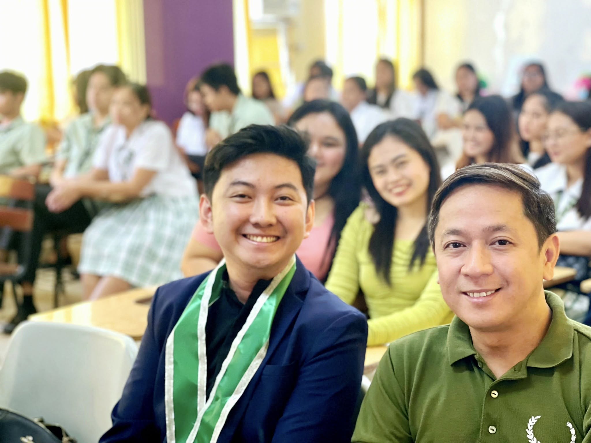 Jayson smiling with a faculty member in front of the accountancy student audience
