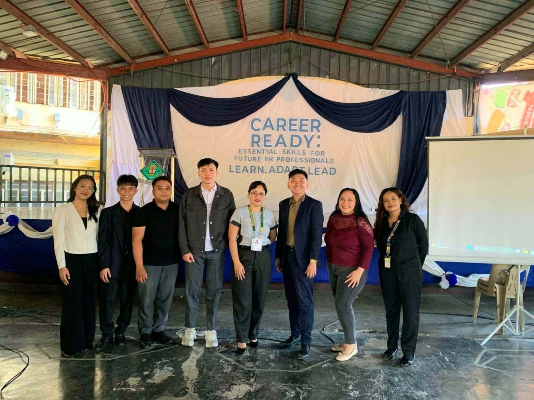 Jayson with faculty and Societas Humana Resource Organization officers in front of the Learn. Adapt. Lead. backdrop