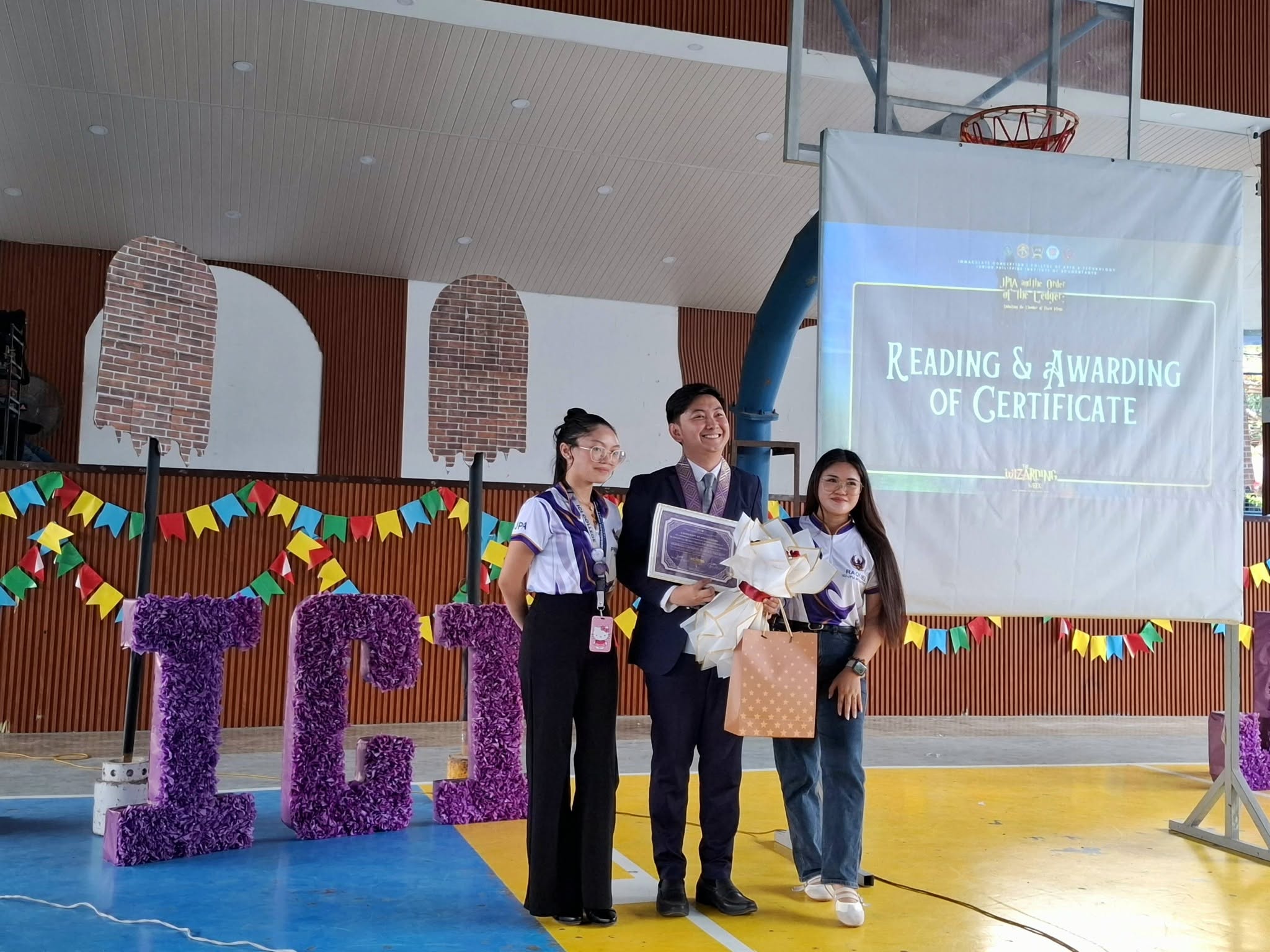 Jayson receiving his certificate and flowers from JPIA student officers during the Reading and Awarding of Certificate