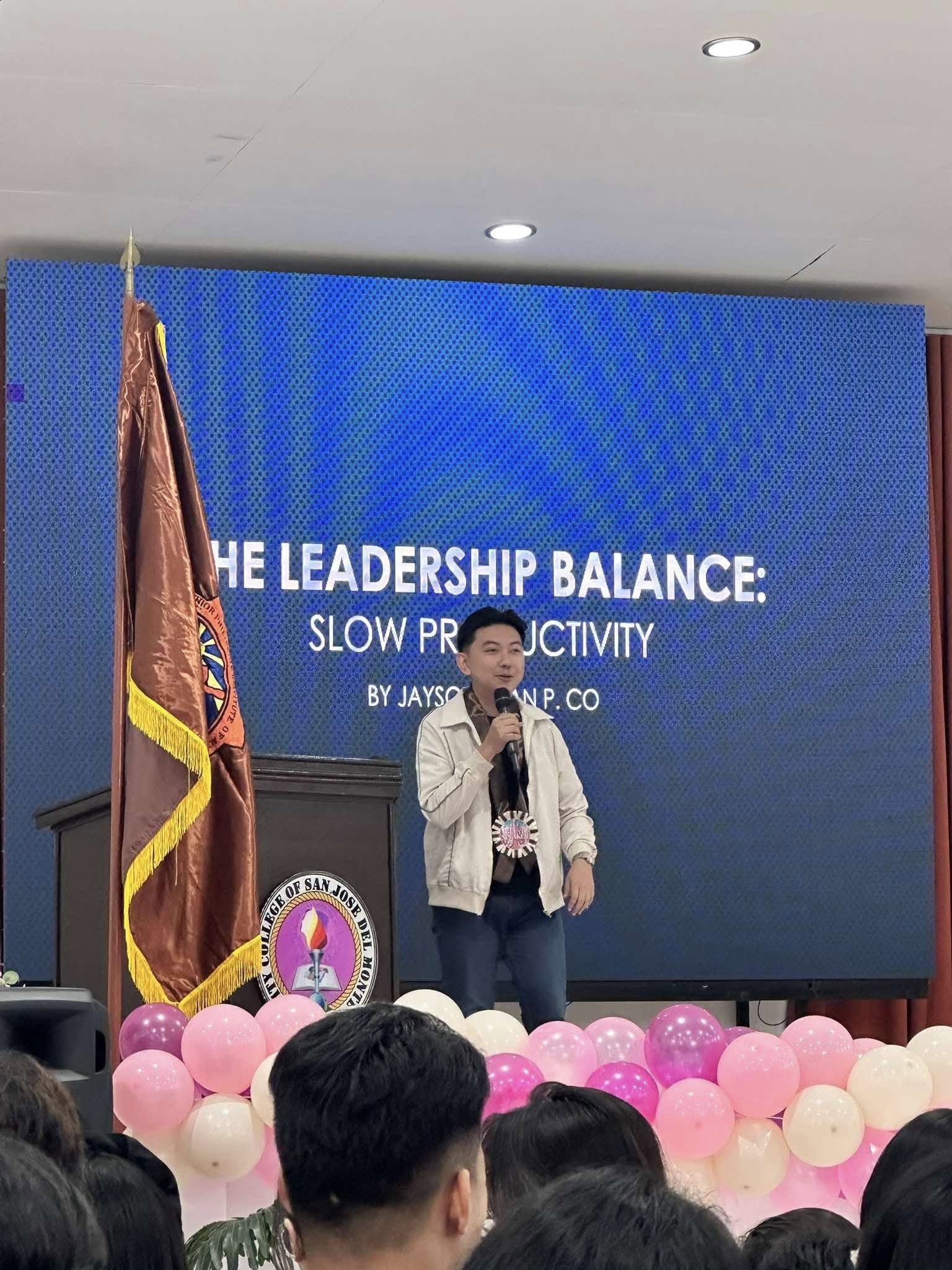 Jayson Ryan Co speaking on stage in front of a slide reading The Leadership Balance: Slow Productivity