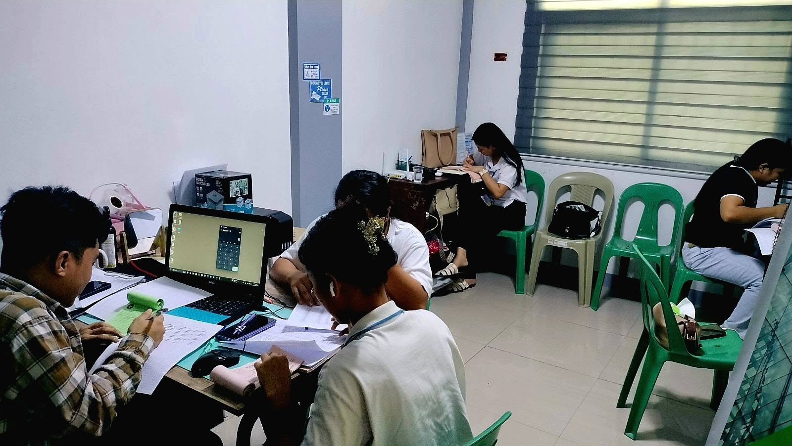 Students bookkeeping around tables with a laptop calculator and ledger papers during the IntegTrust workshop